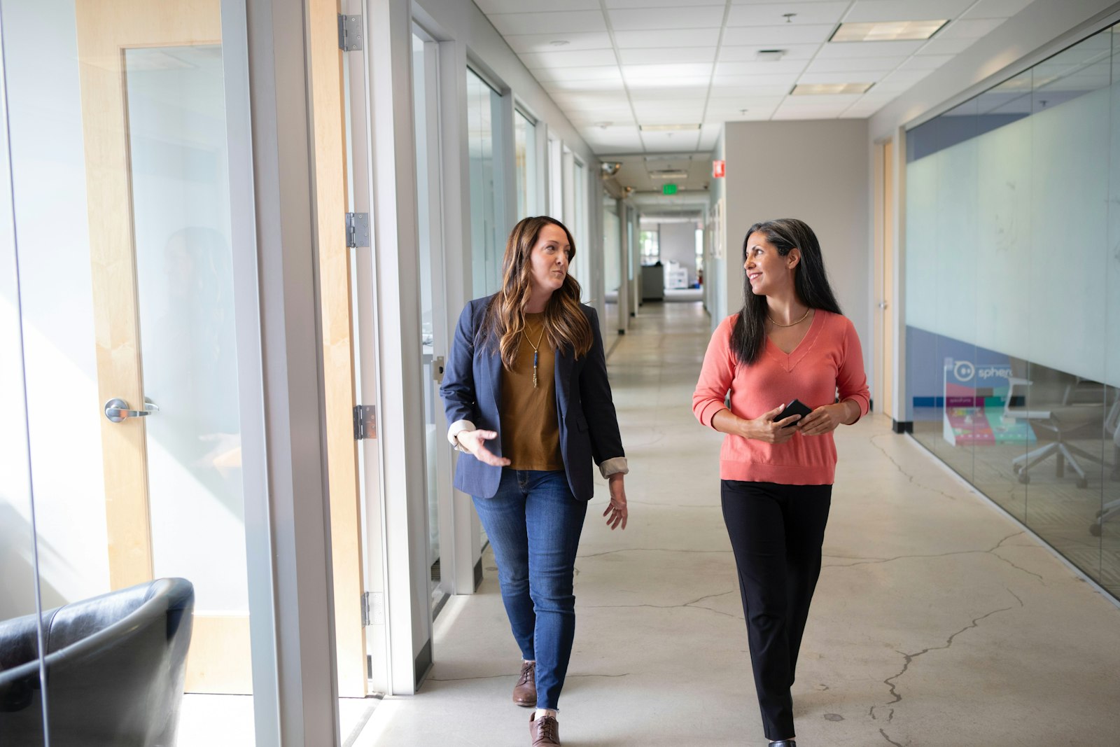 Ruth Calloway and a colleague walking an office corridor in conversation